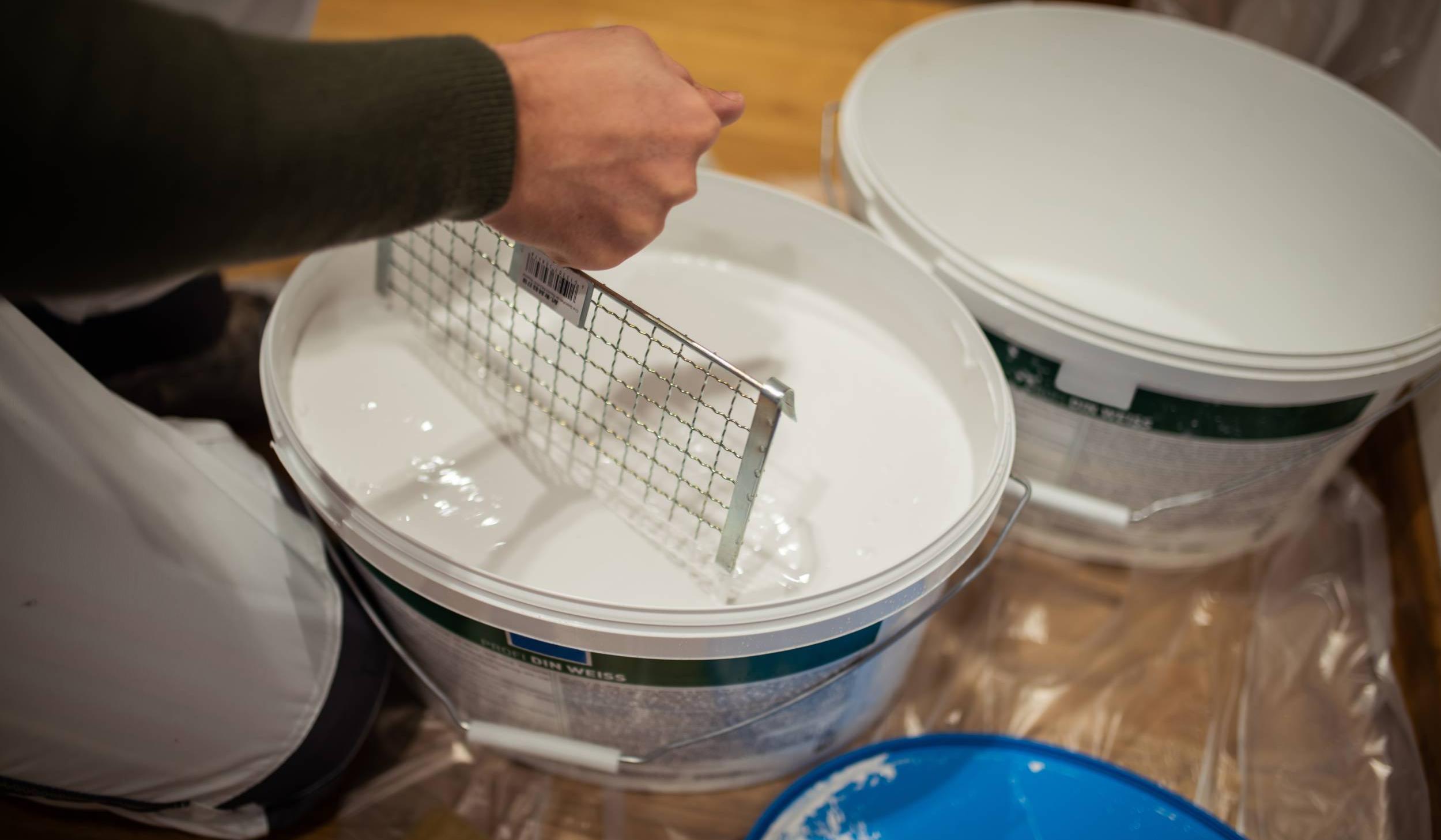 Zwei Eimer mit weißer Wandfarbe auf Folie, 2020